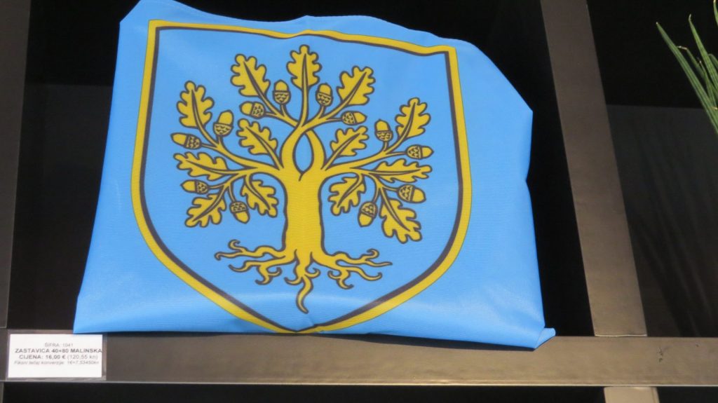 Grb općine Malinska - Dubašnica predstavlja zlatni hrast medunac utopljen u plavetnilo mora