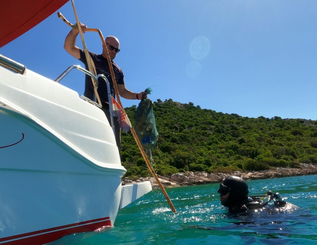 Izvlačenje smeća s podmorja u čamac / Foto: FB Ronilački klub Murter Kornati